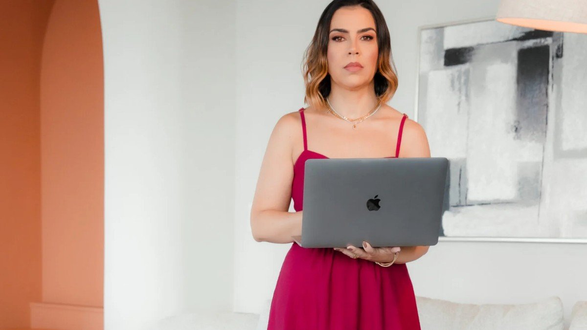 Luciana Prates segurando um notebook aberto, em pé